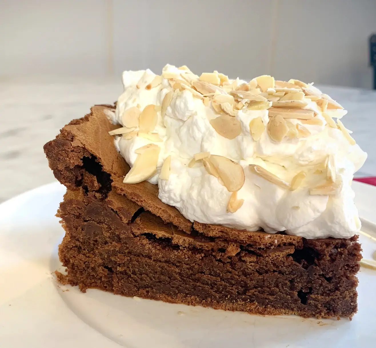 flourless chocolate torte topped with whipped cream and almond slivers