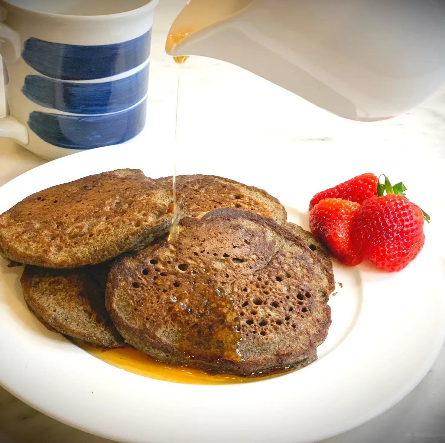 Buckwheat pancakes plated with syrup poured on top