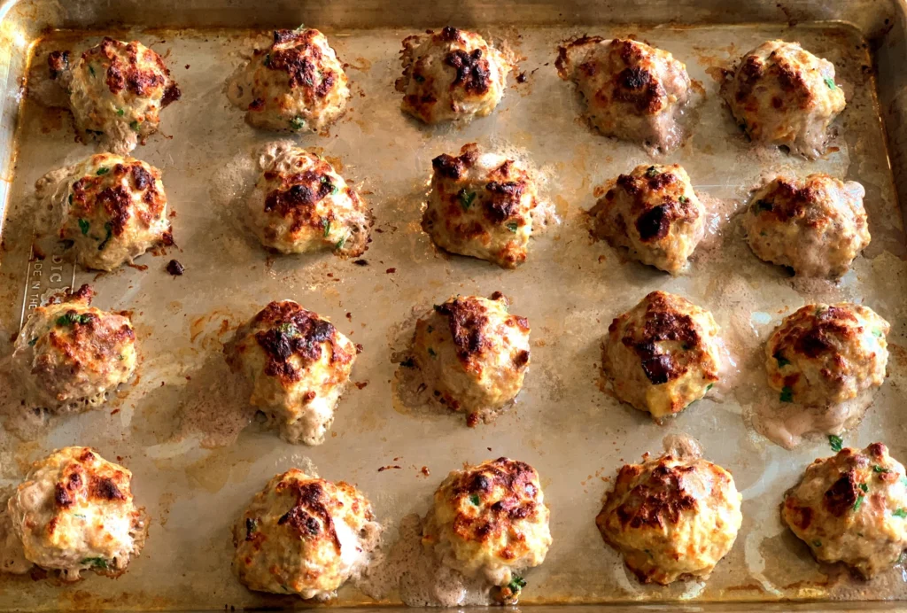 Meatballs lined up on baking sheet