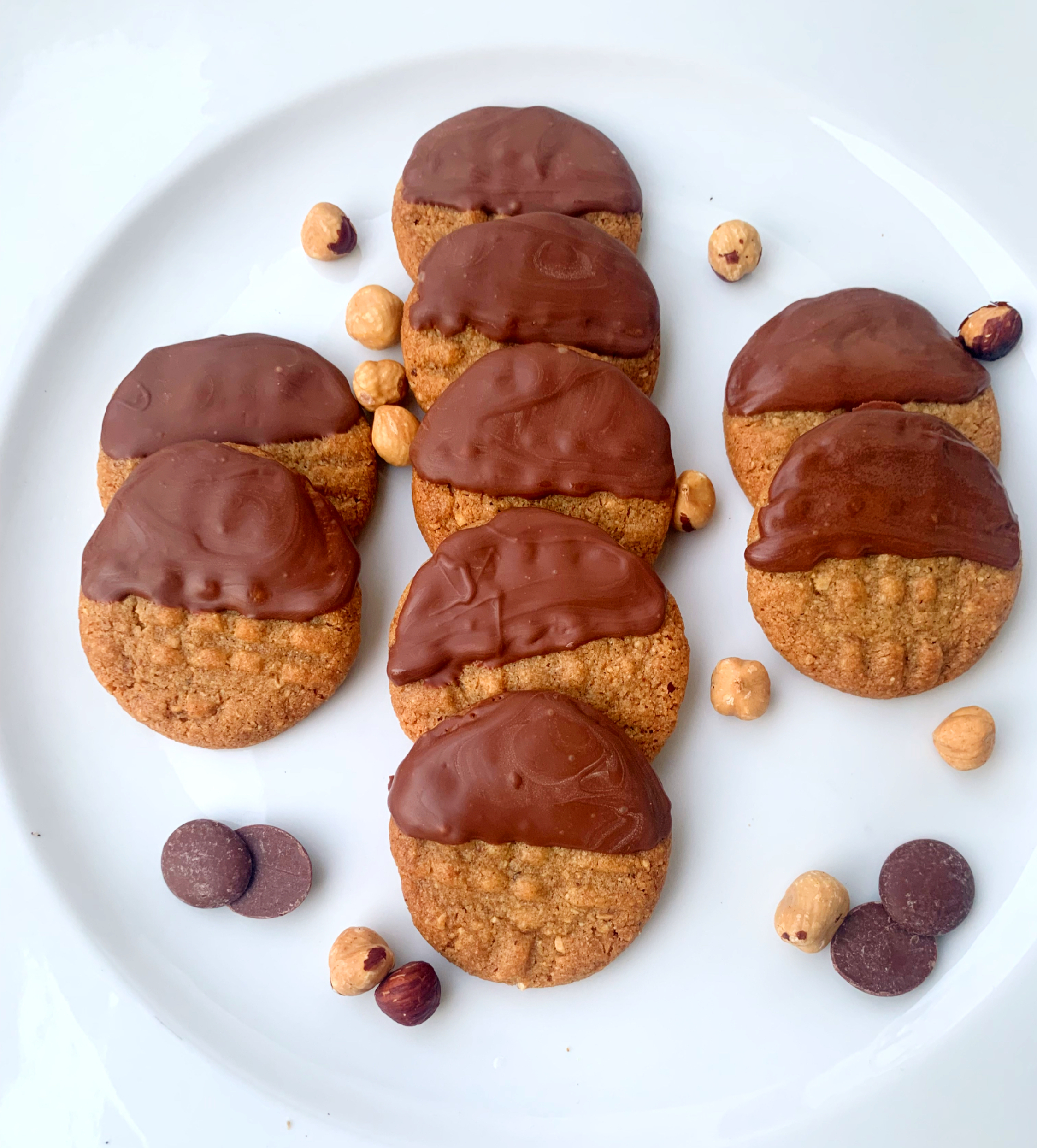Hazel Moon Cookies Dipped in Chocolate on a serving platter surrounded by hazelnuts