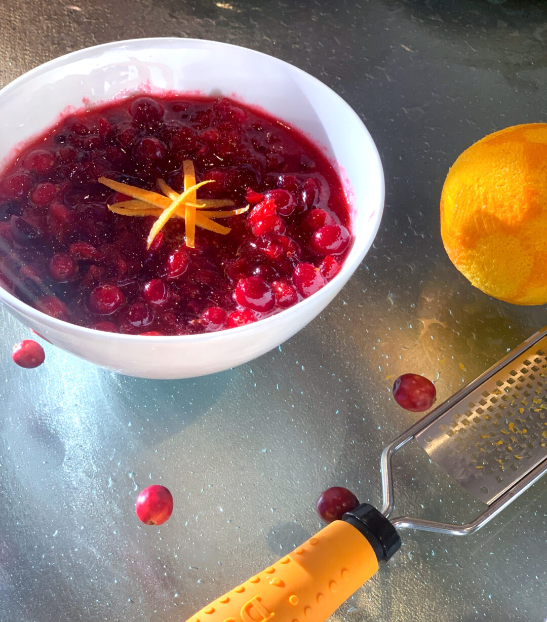 Cranberry Sauce in white bowl with zested orange and zester