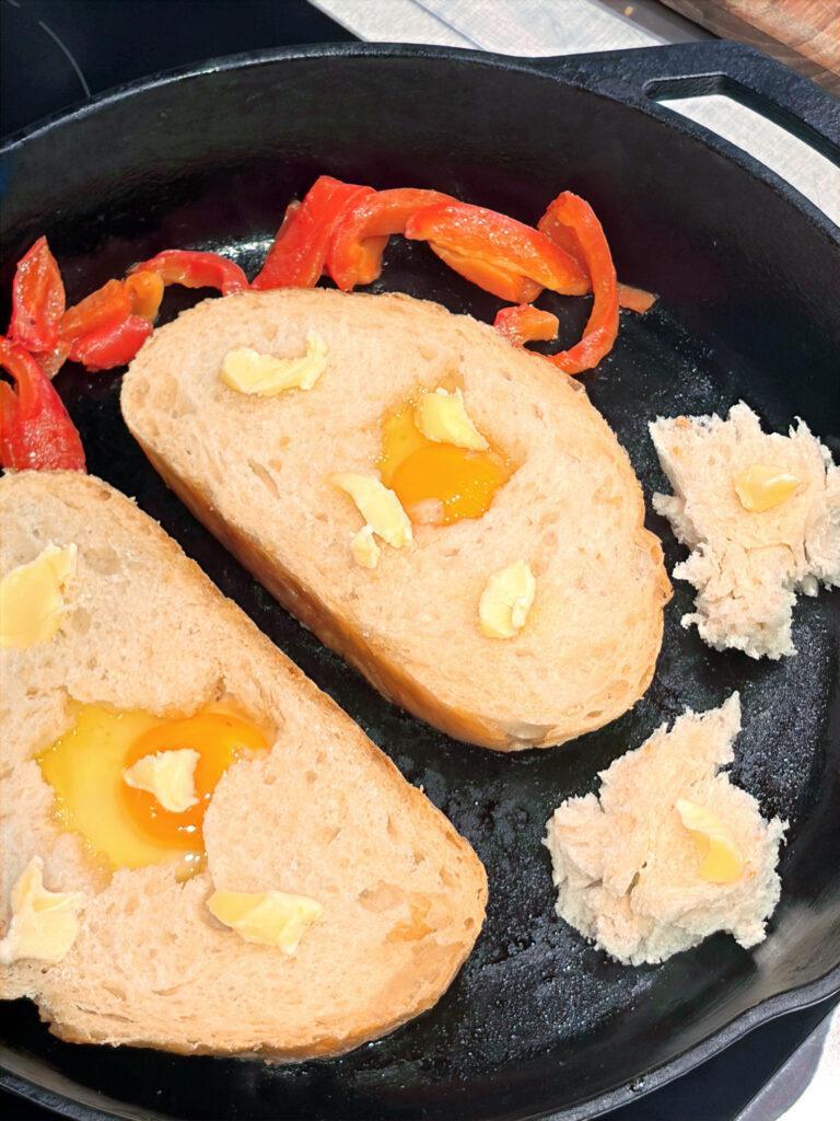 Egg Boats cooking in a cast iron pan with roasted peppers